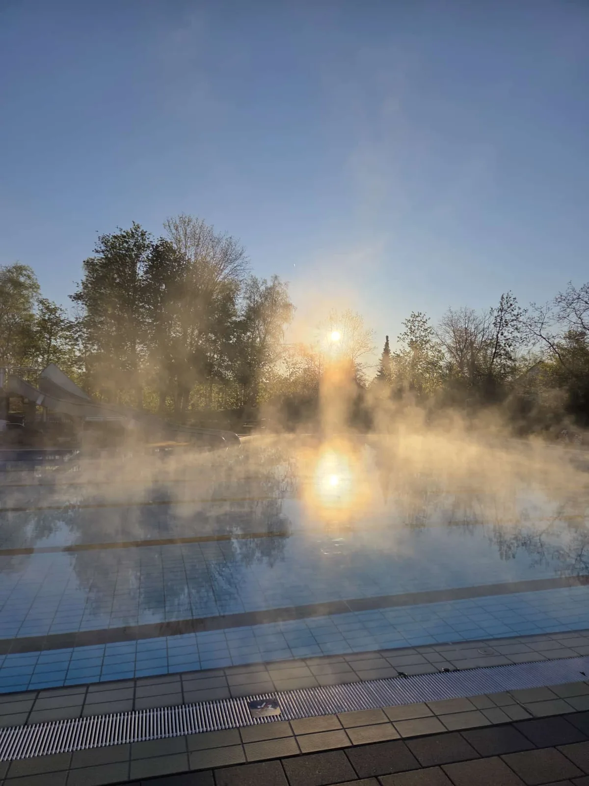 Morgenstimmung über dem dampfenden Schwimmerbecken bei Sonnenaufgang