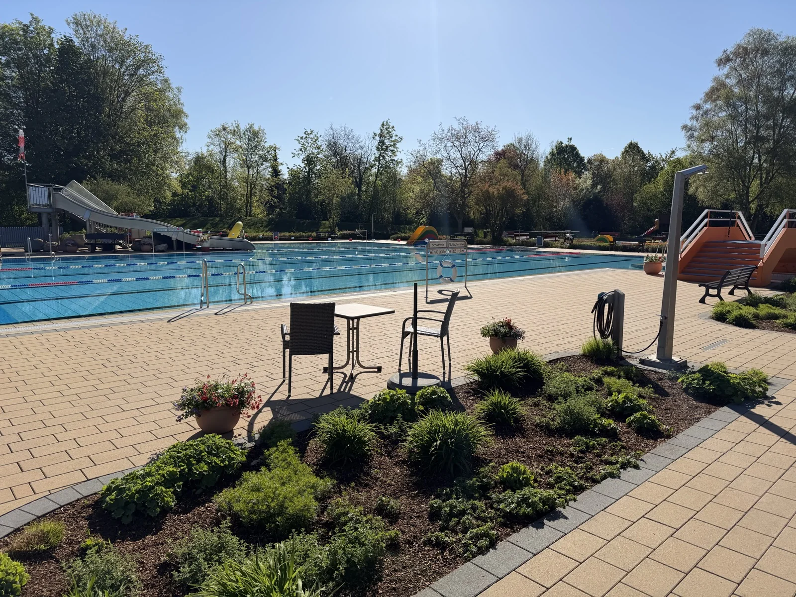 Schwimmerbecken am Morgen der Saisoneröffnung 2026 – Sonne, blauer Himmel, frische Bepflanzung am Beckenrand